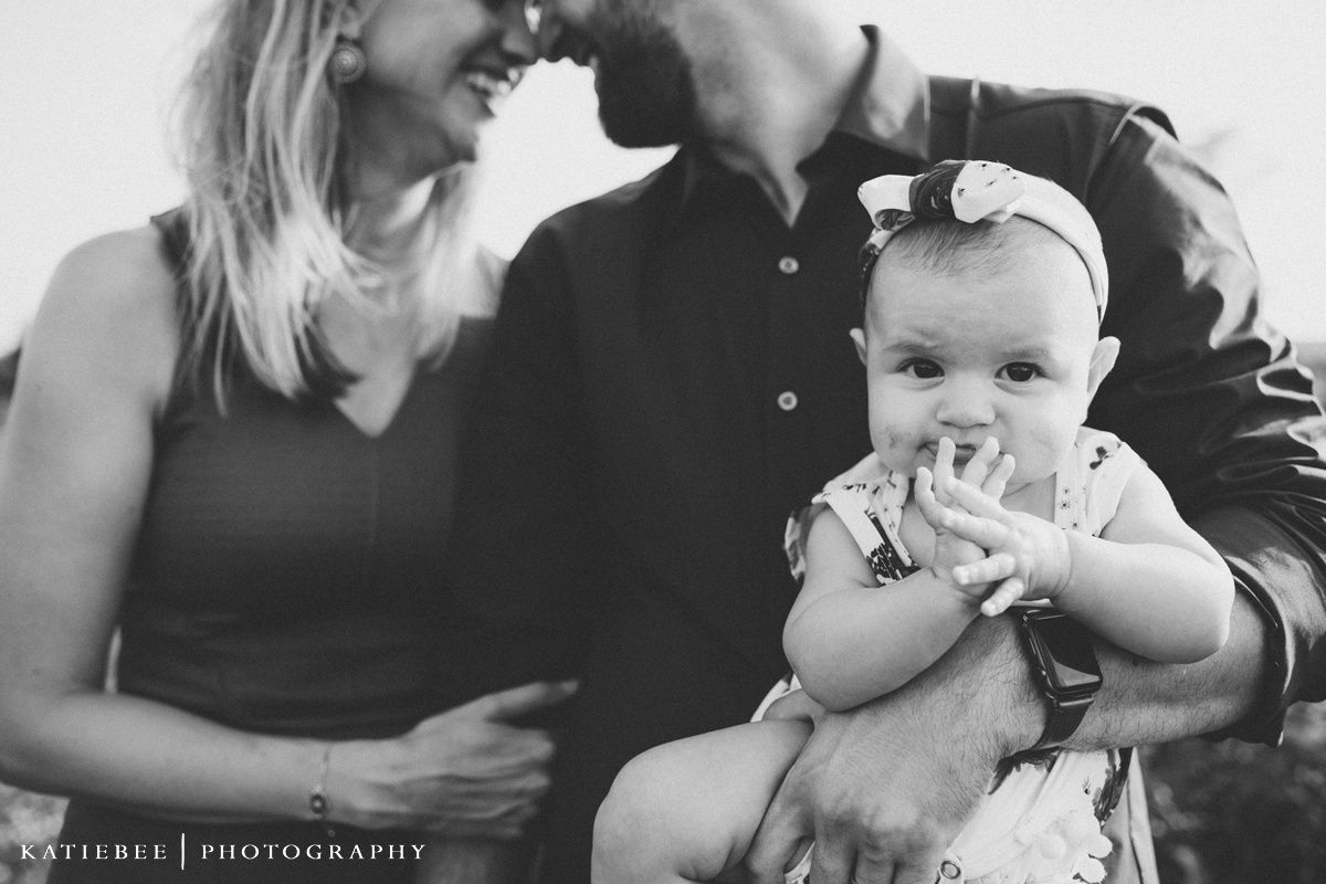 Black and white intimate family portrait showing a sweet moment with an infant.