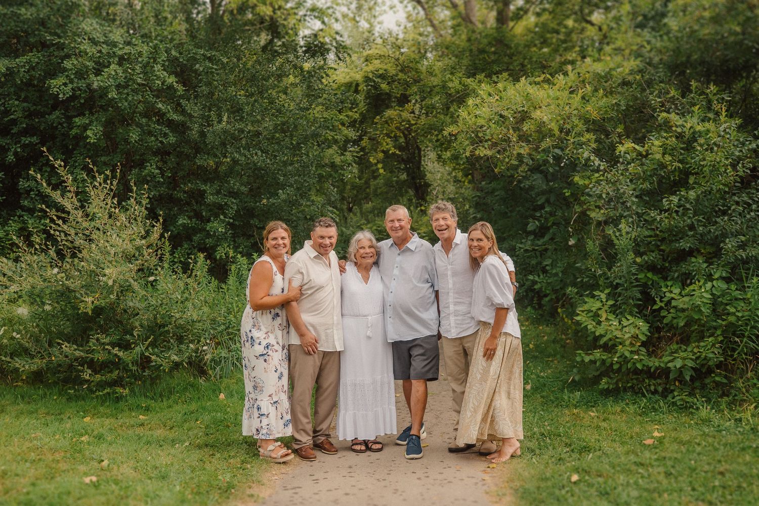 Group wearing coordinated neutral outfits poses together in a scenic outdoor setting.