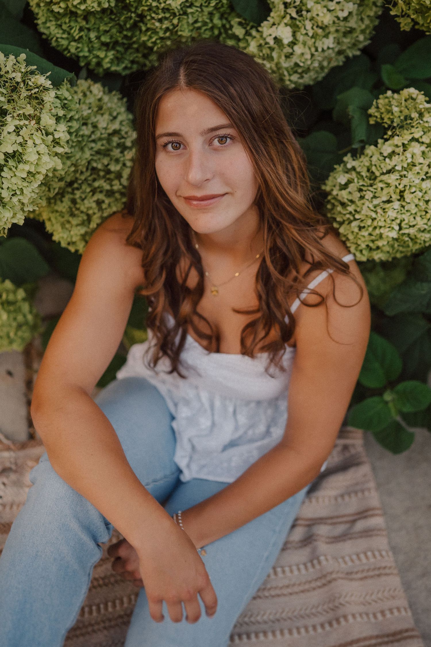Natural light portrait session against a backdrop of white hydrangea blooms and greenery.