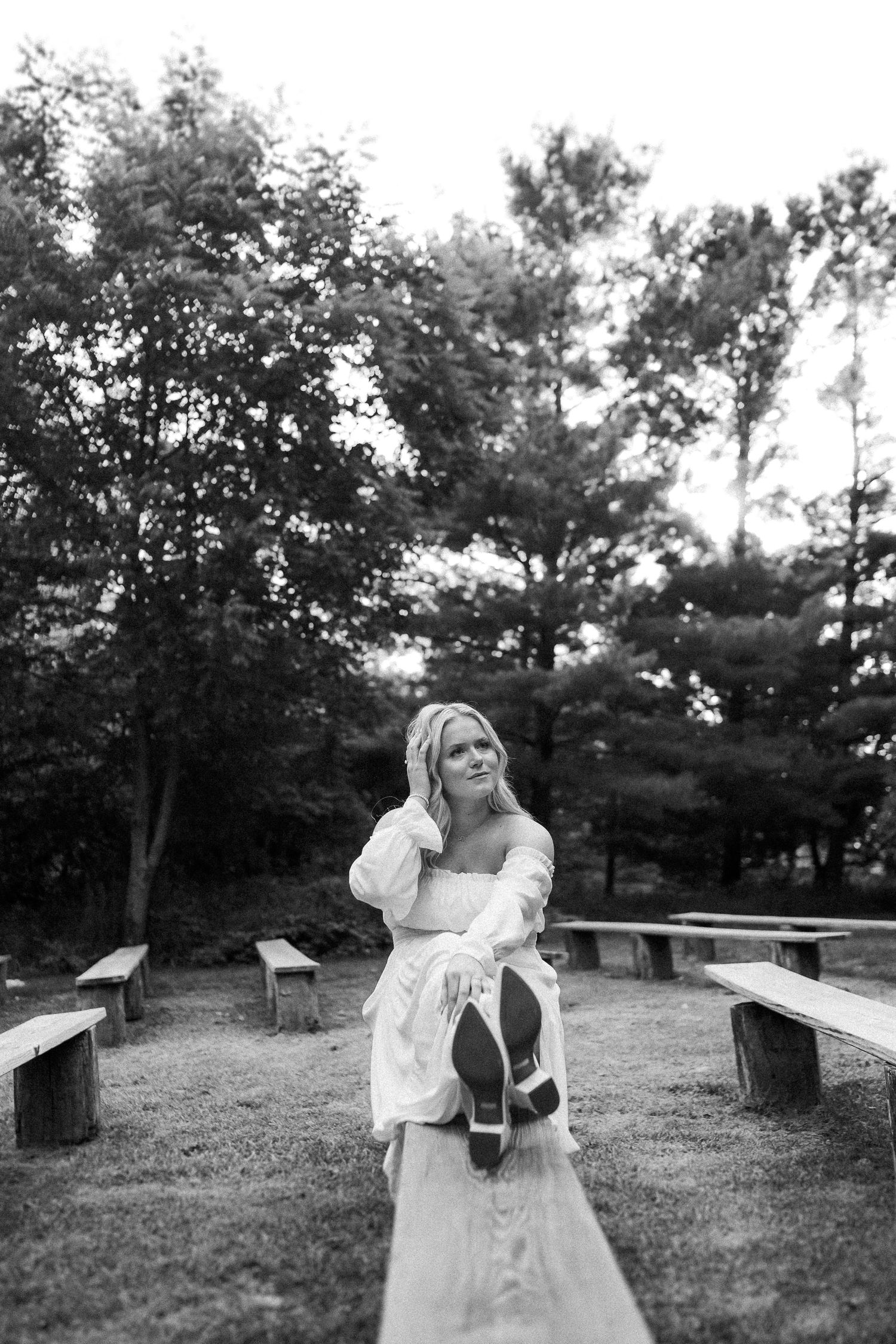 Black and white portrait of someone in a flowing dress on park benches.