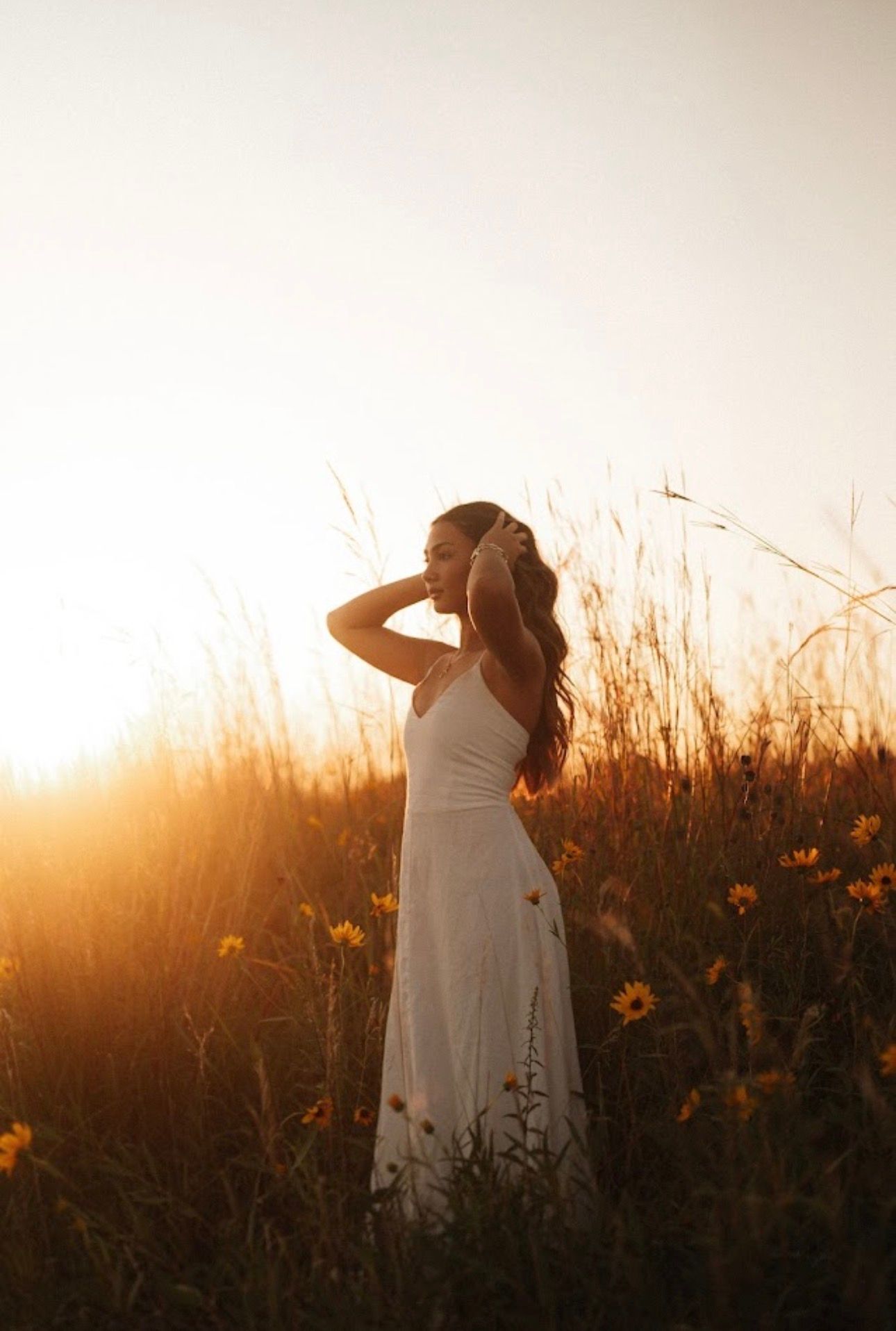 Ethereal white dress silhouette against tall grass during golden sunset.