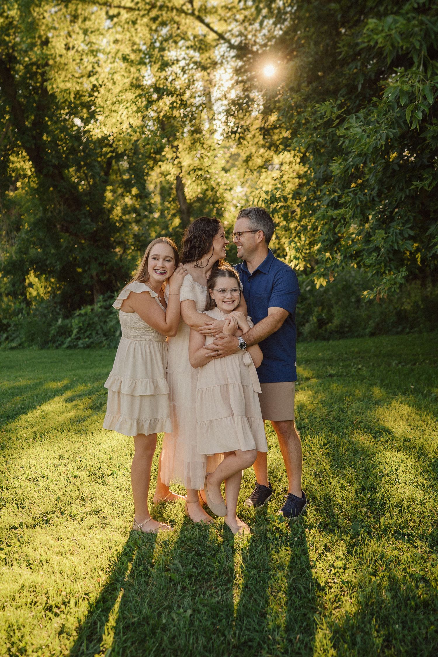 Family shares tender moments together in a lush green park setting during sunset.