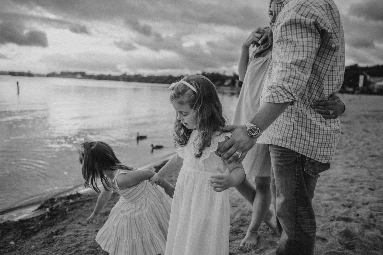 A tender moment at the beach showing family silhouettes against dramatic cloudy skies.