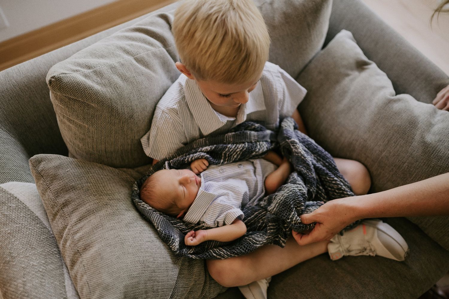 Cozy scene of children bonding on grey sofa with soft natural lighting.