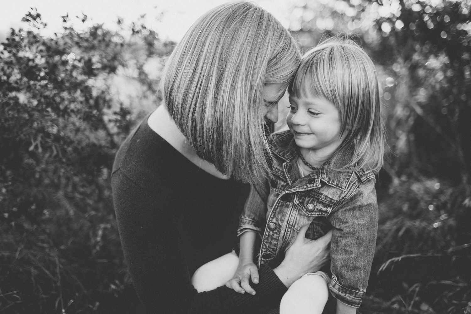 Black and white portrait of two people sharing an intimate moment outdoors.