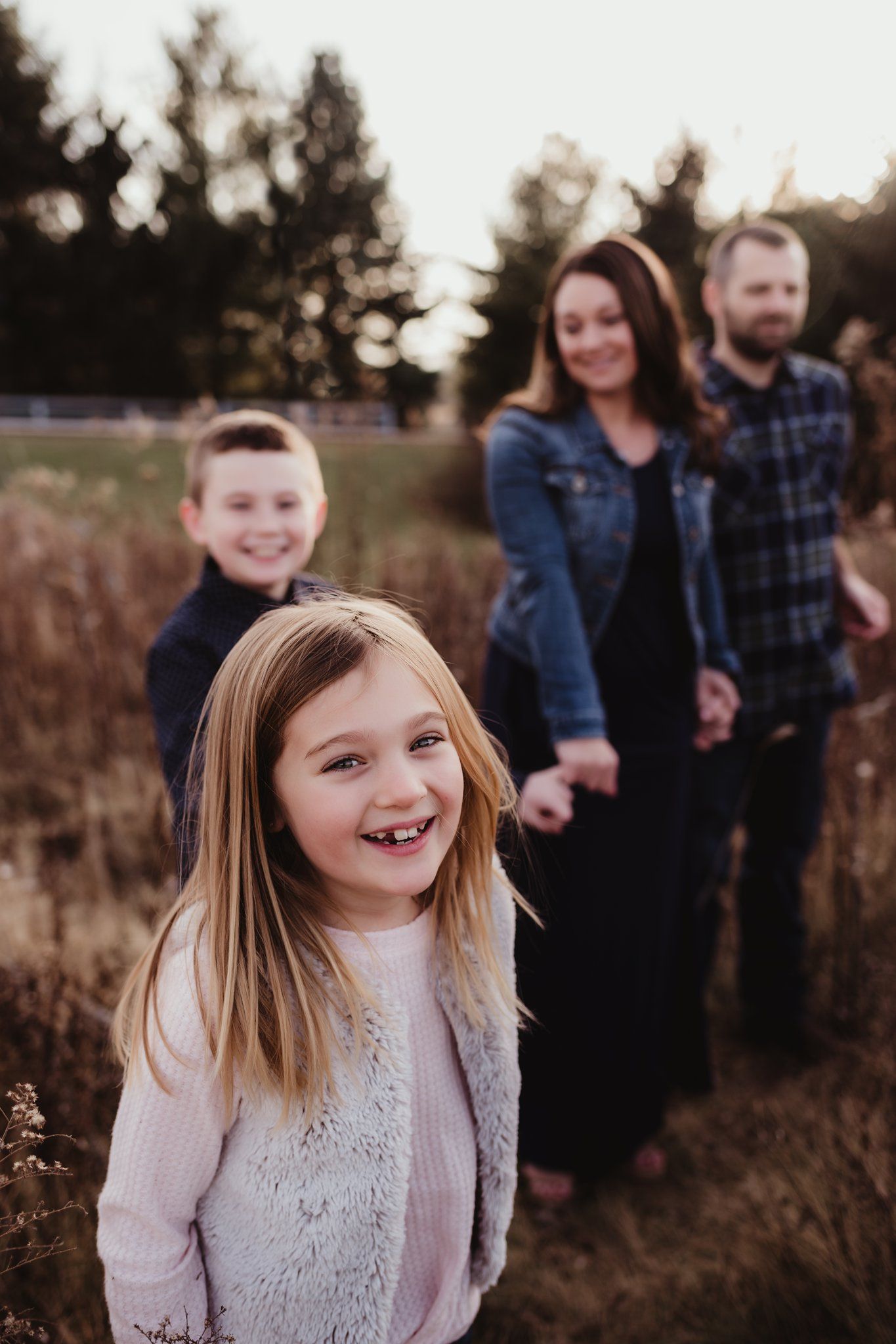 A casual family photo taken at sunset in a field of tall grass.
