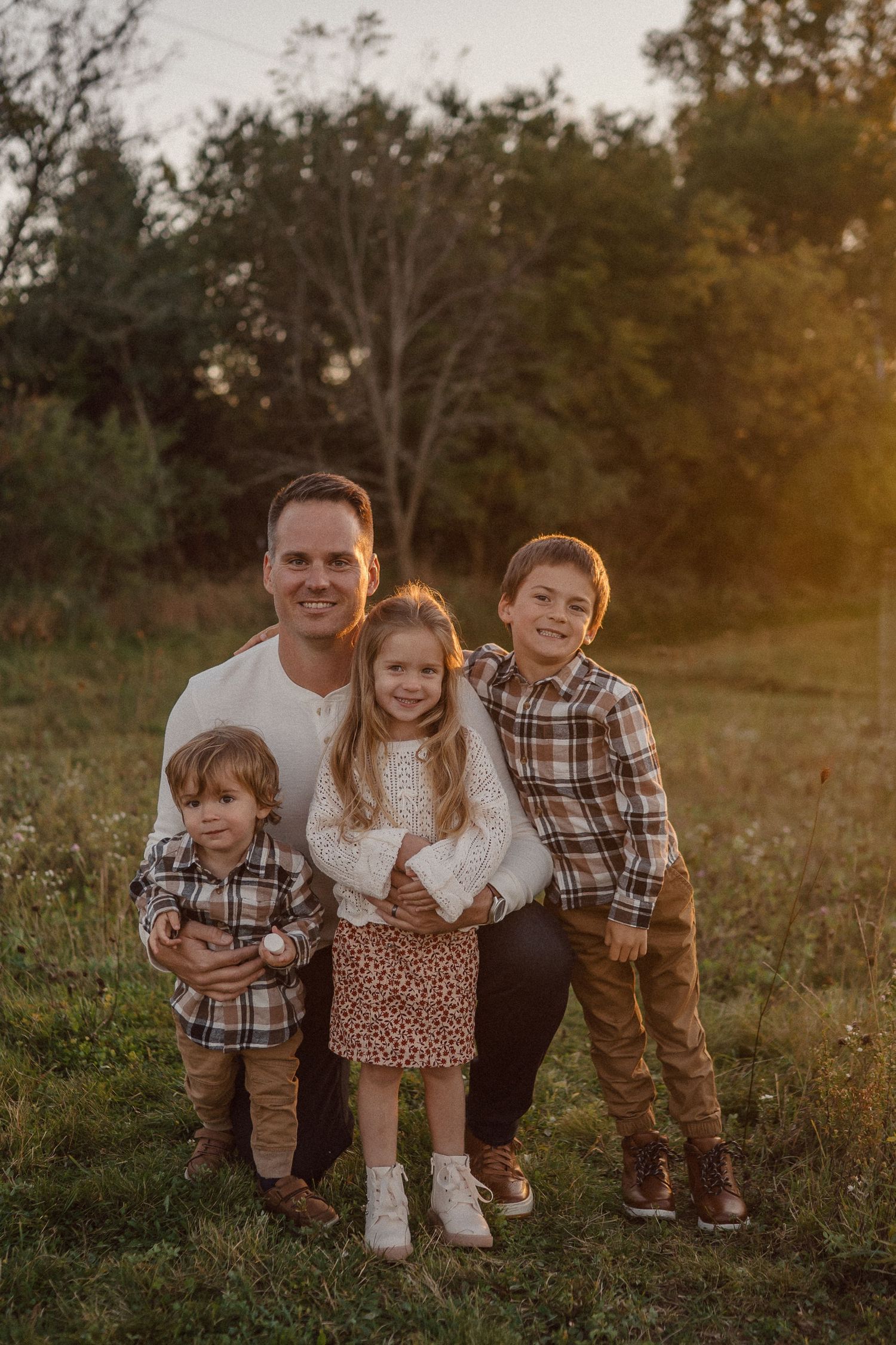 A group poses together on grass during a warm sunset photoshoot.