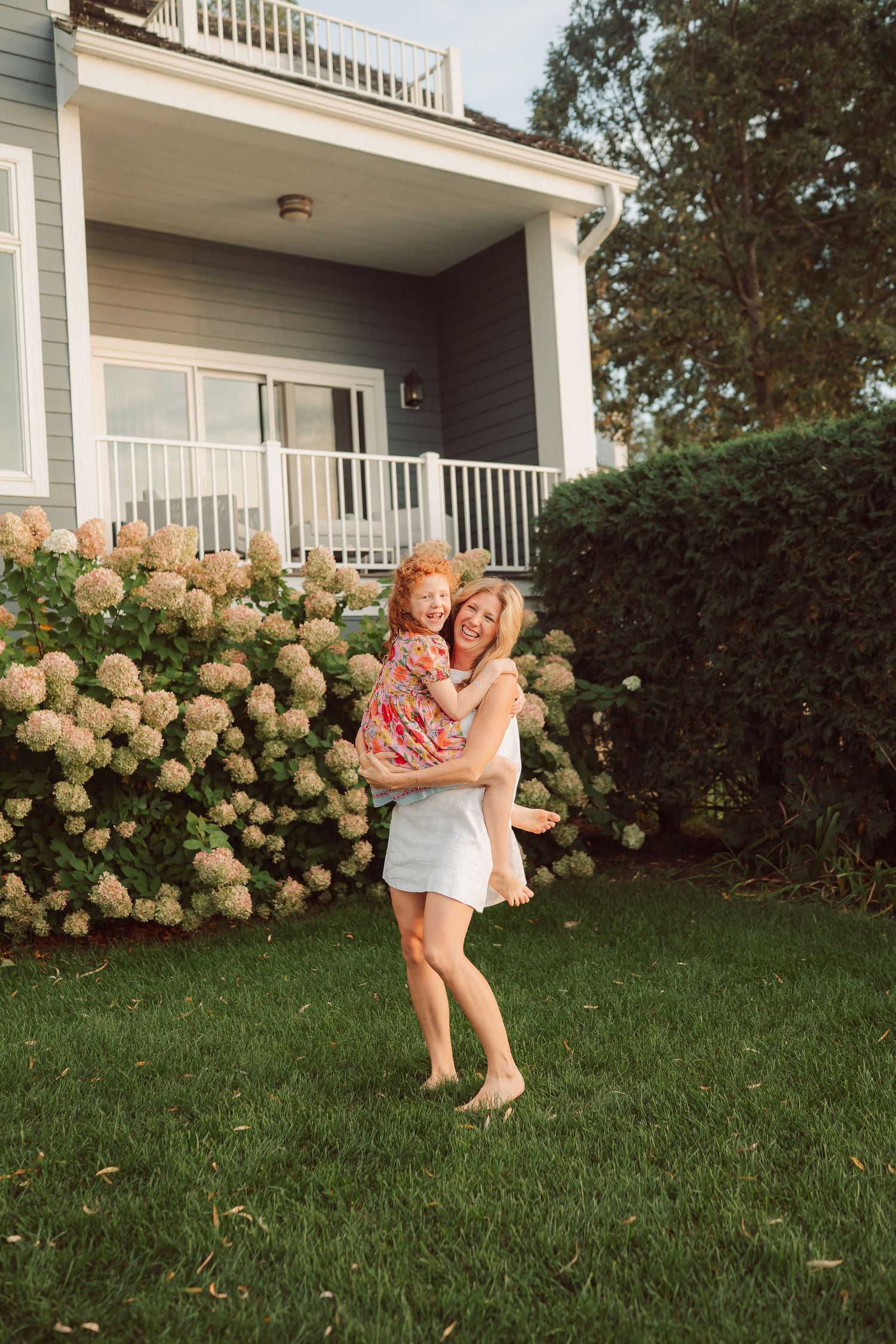 Candid moments of joy captured in front of a house with blooming hydrangea bushes.