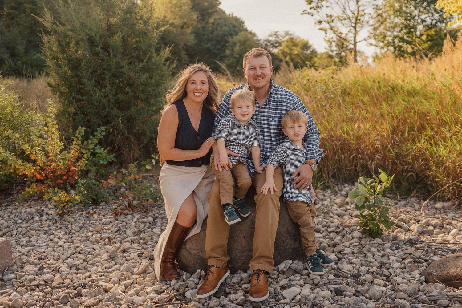 A family enjoys a tender moment together during a golden hour photoshoot in a natural outdoor setting.