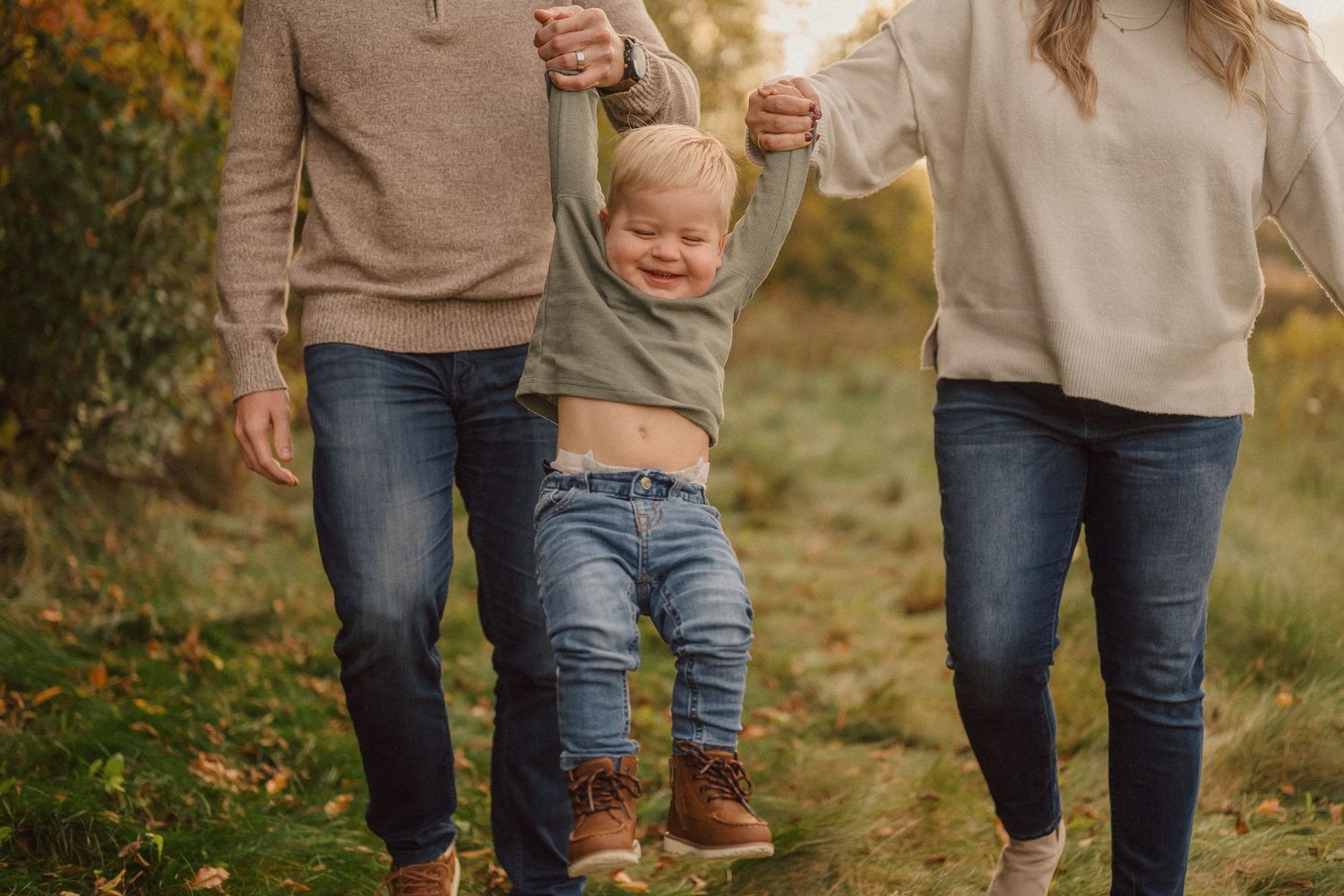 Family walking together through autumn field during golden hour sunset session.