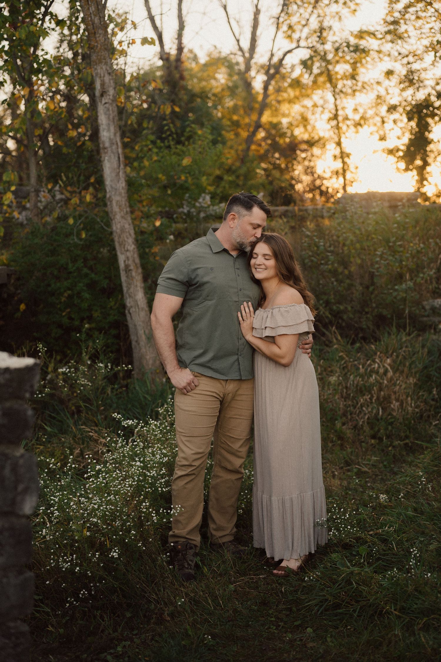 Couple sharing an intimate moment in a wildflower field at sunset.