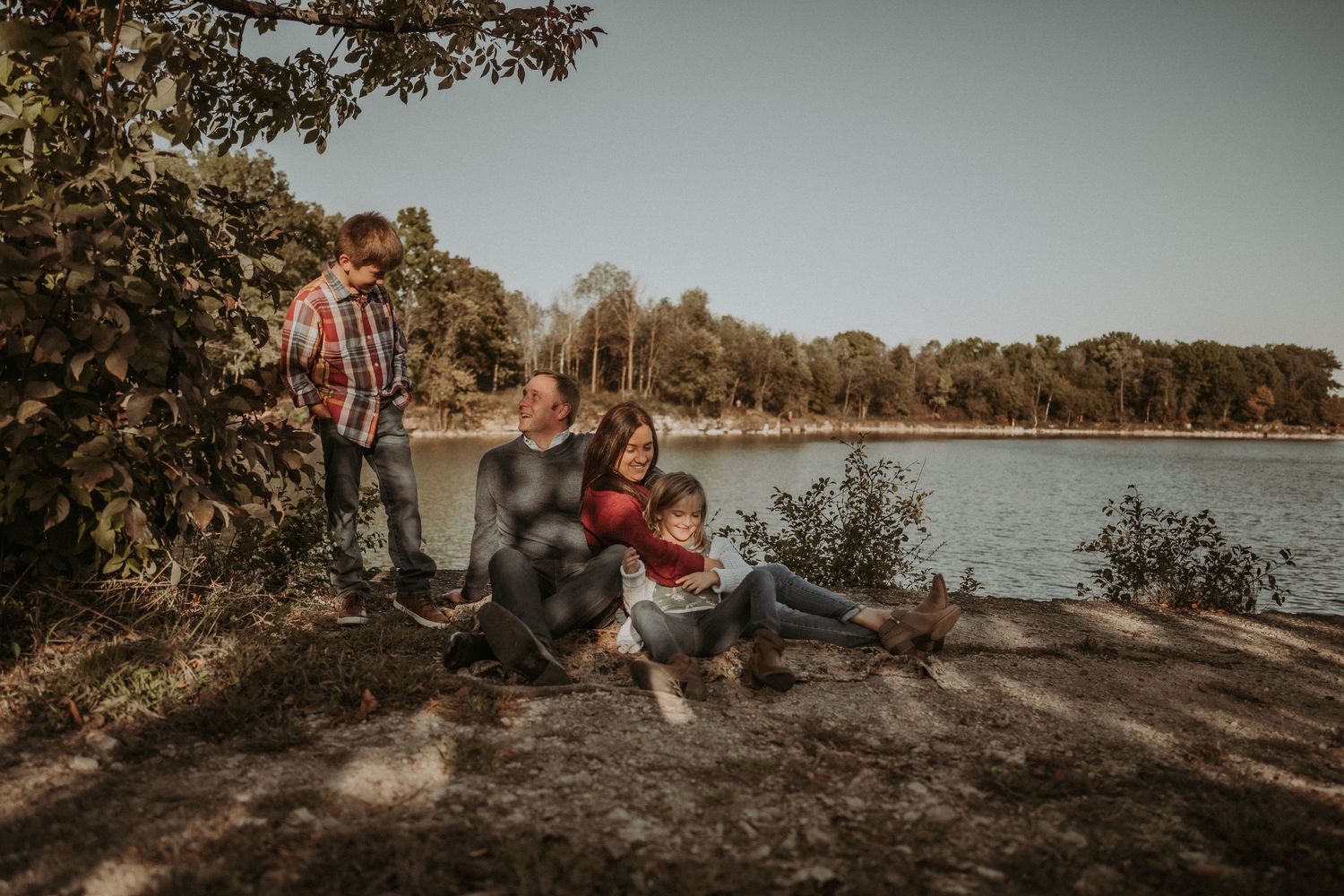 A family enjoys quality time together by a peaceful lake surrounded by autumn trees.