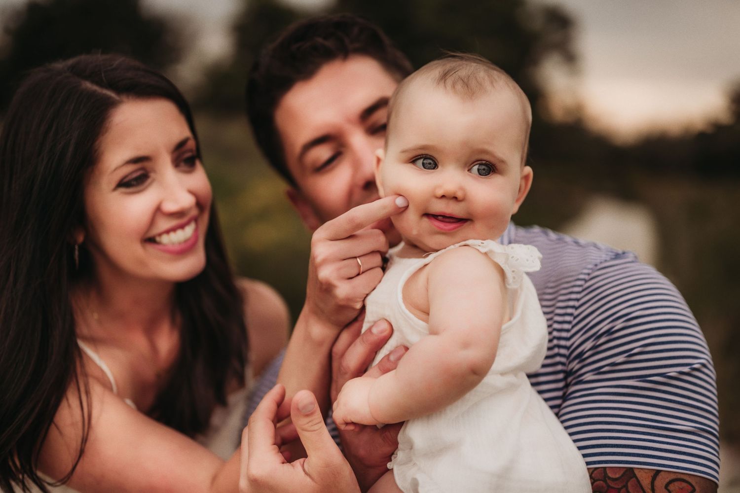 Happy family shares a tender moment with their baby outdoors.