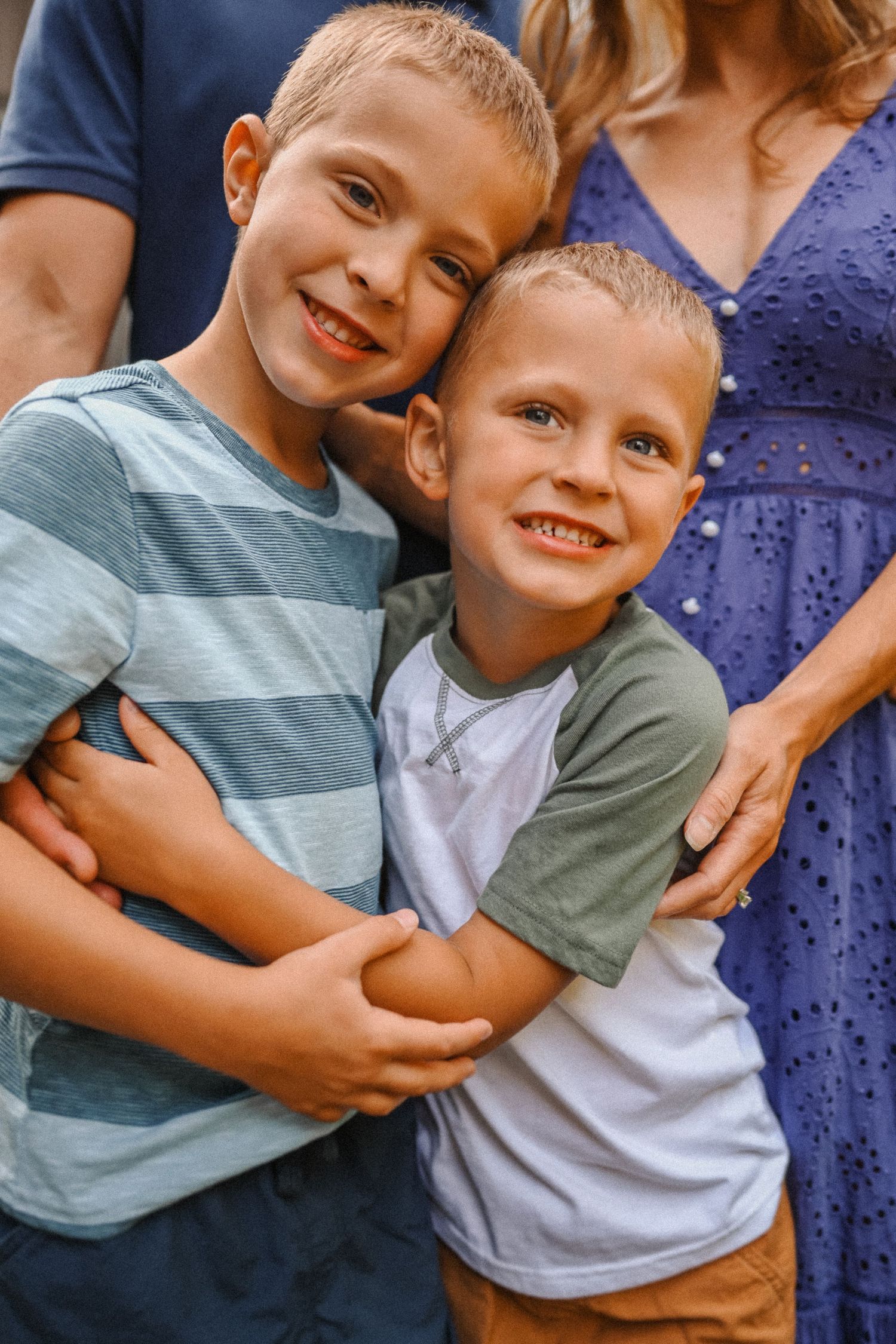 Two young siblings embracing and smiling brightly at the camera.