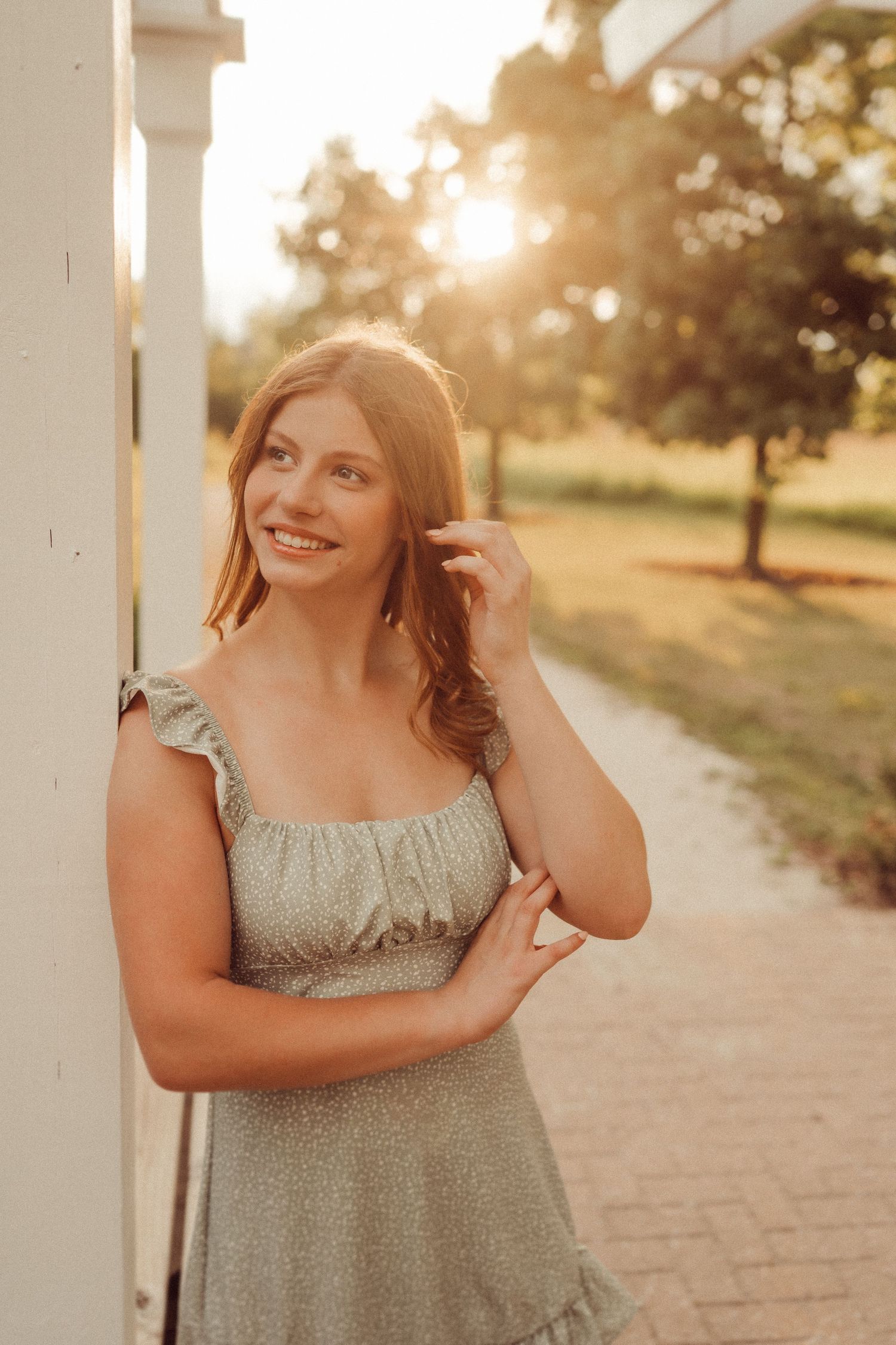 Golden hour portrait against white column with warm backlighting.