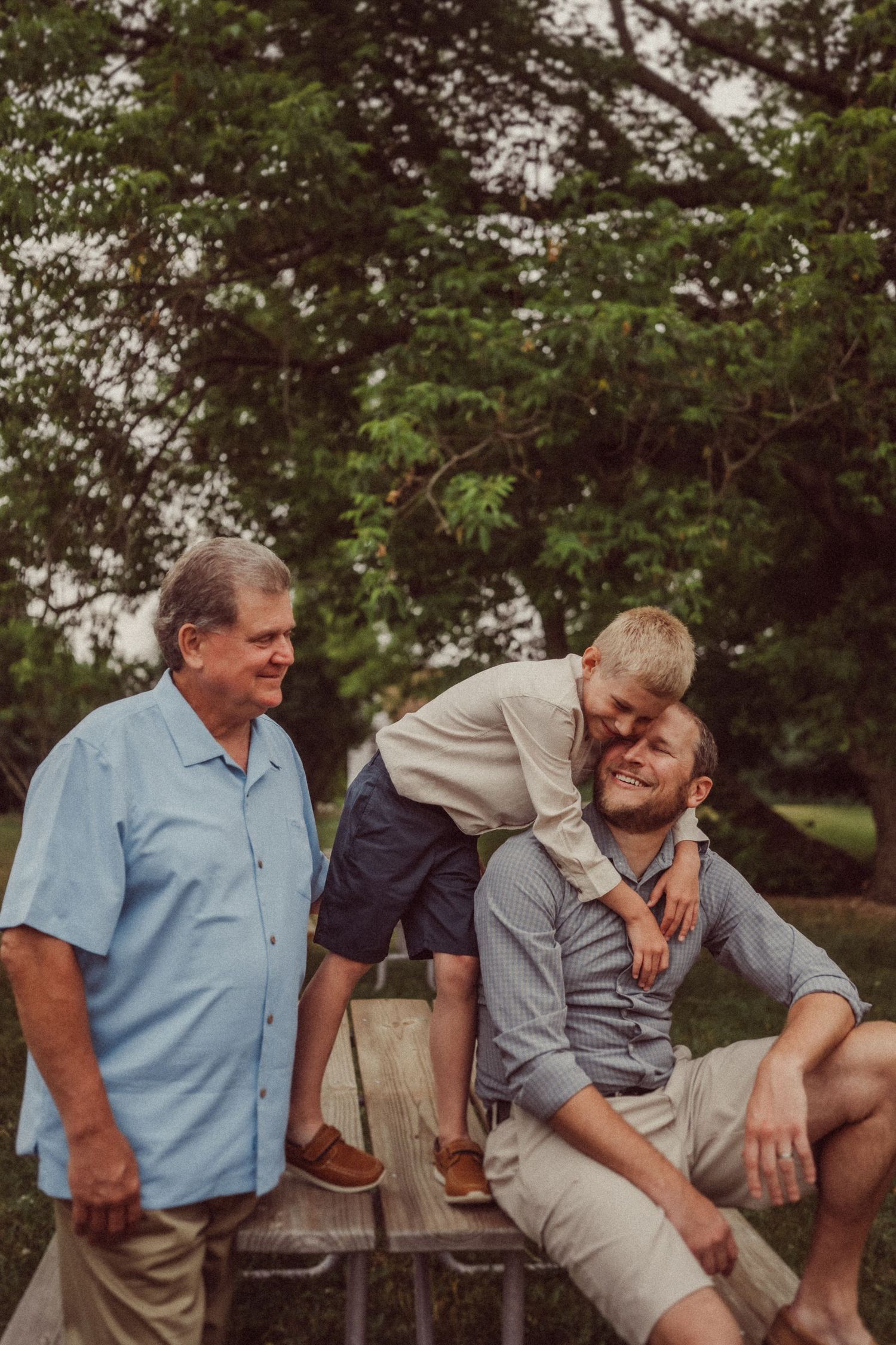 Three people share a playful moment while sitting on outdoor steps.