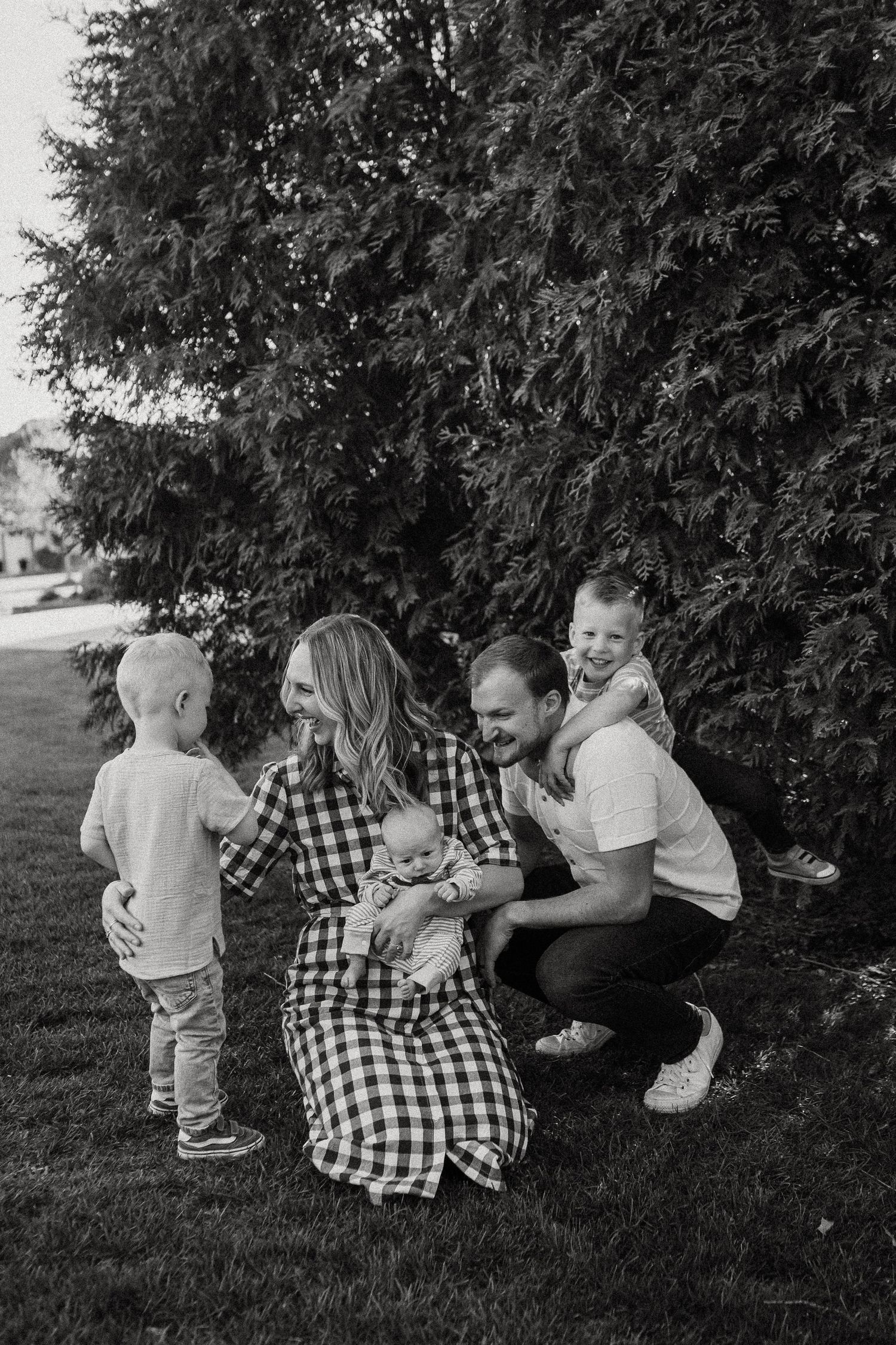 Black and white photo of a happy family of five gathered together on a green lawn.