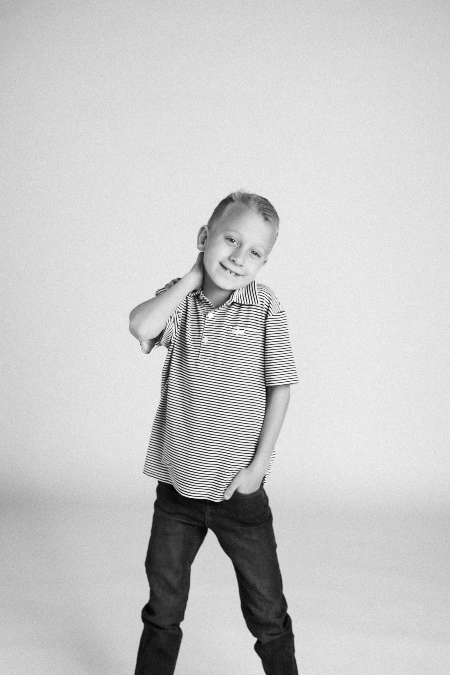 Black and white photo series of a child in a striped polo shirt and jeans posing playfully against a light background.