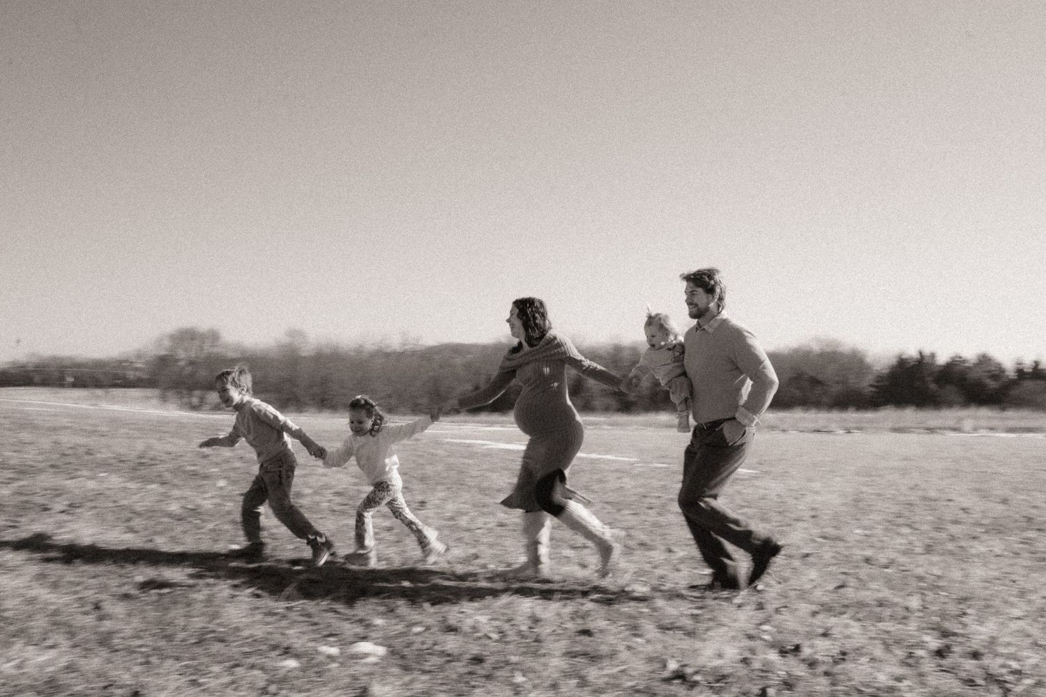 A sequence of black and white photographs showing people falling on a beach in a playful manner.