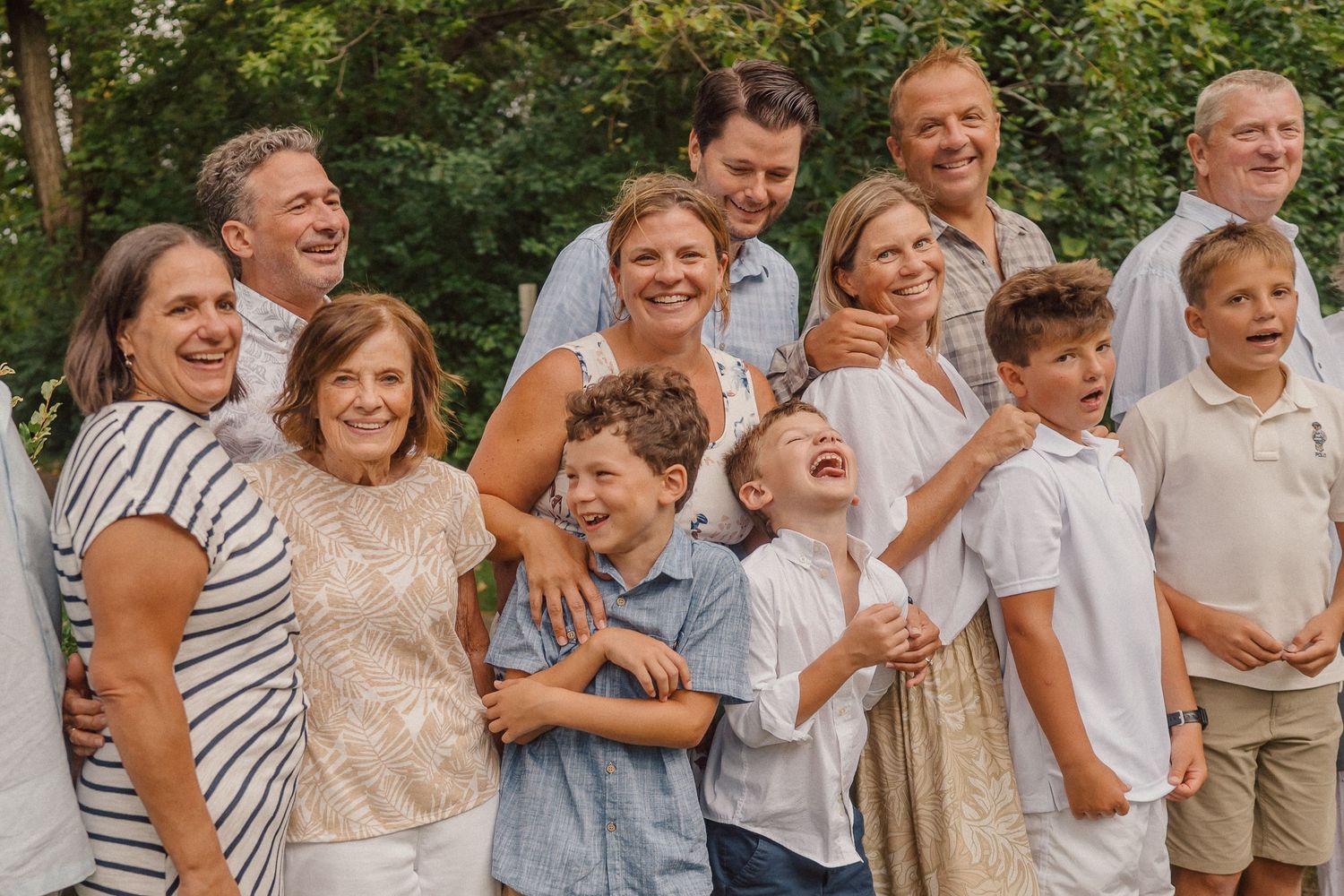 A joyful multi-generational family poses together outdoors for a casual portrait on a sunny day.