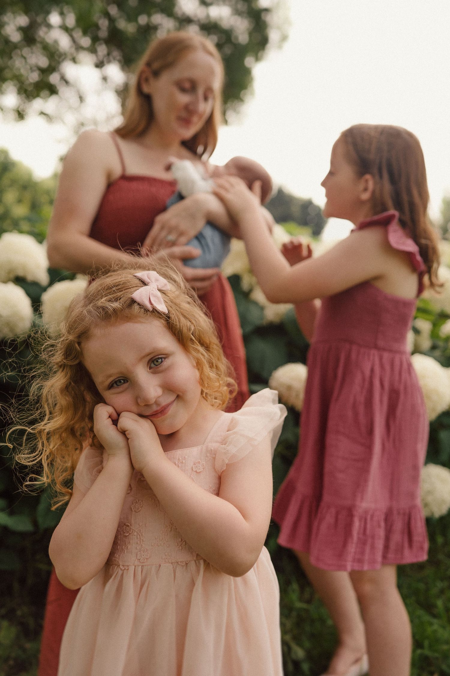A joyful outdoor portrait with white hydrangeas creating a beautiful natural backdrop in soft evening light.