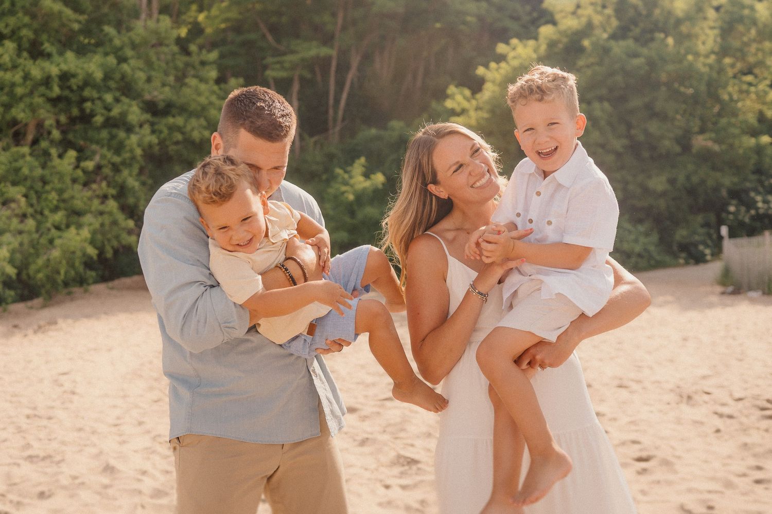Candid family photo session on a sunny beach with everyone laughing.
