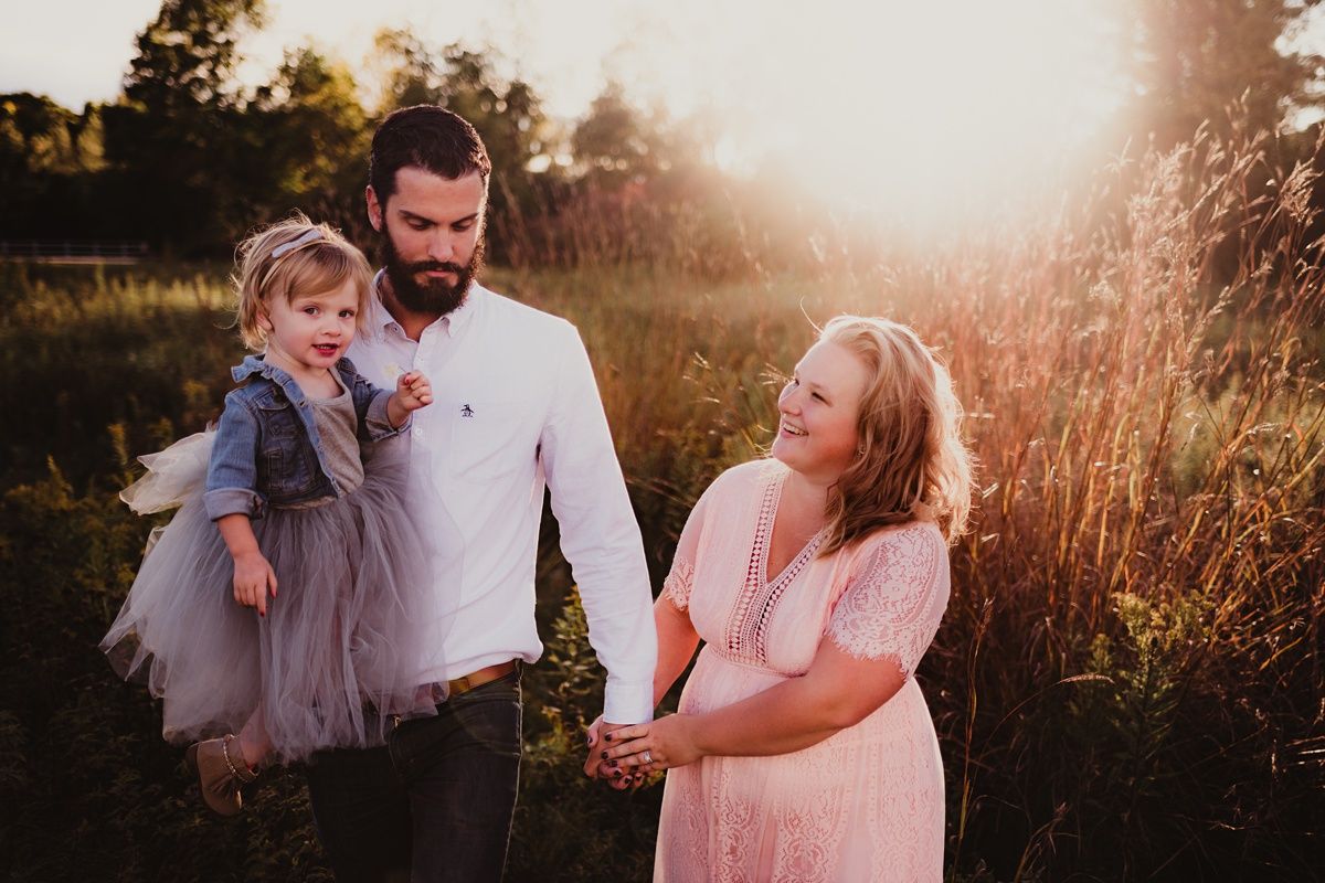 Sunset family portrait in a field showing joyful interaction and special bonding moment.