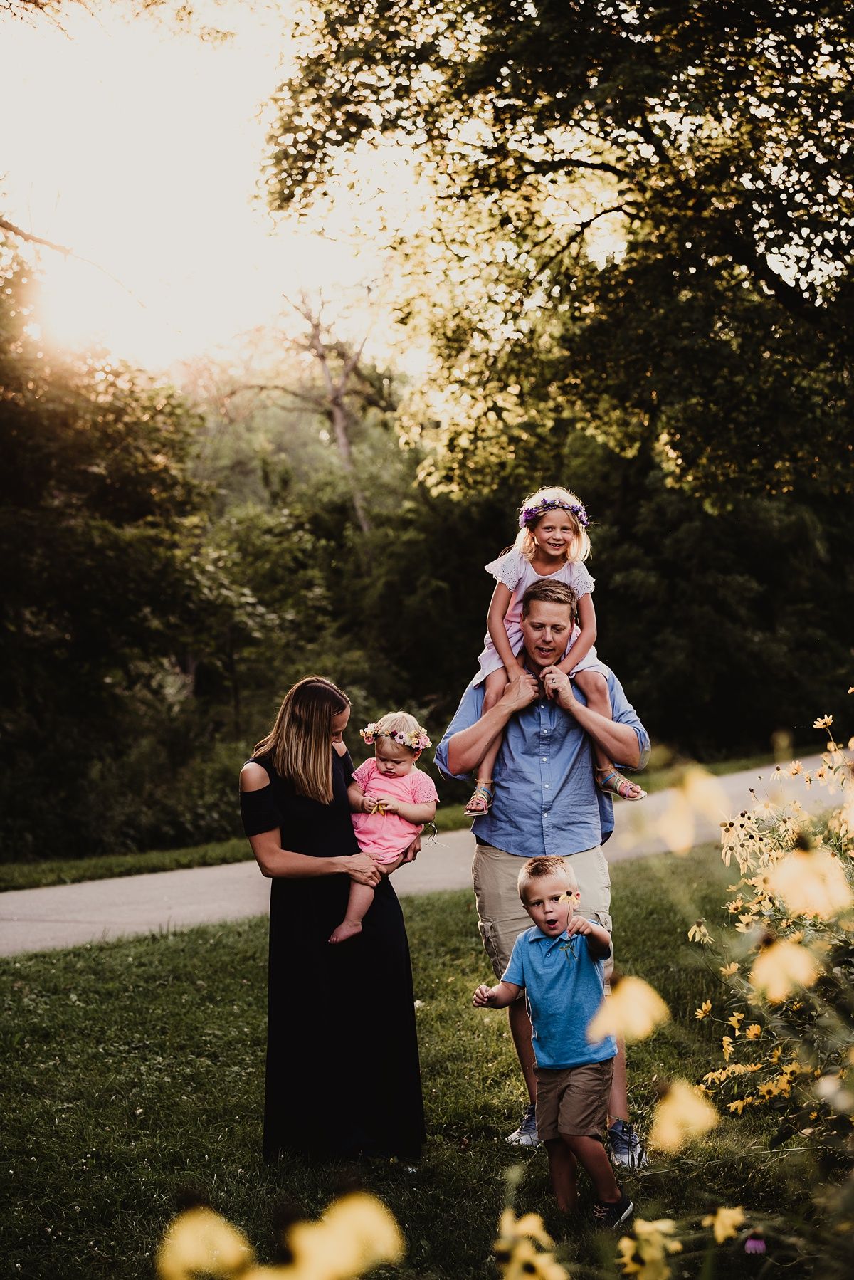 A family enjoying a sunset photoshoot in a park with golden light filtering through tree branches.