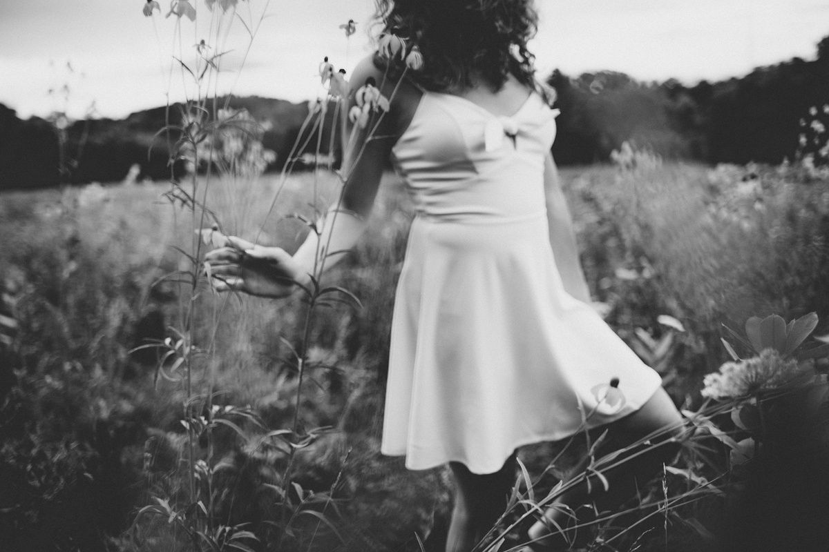 Black and white image of flowing dress movement in wildflower field.