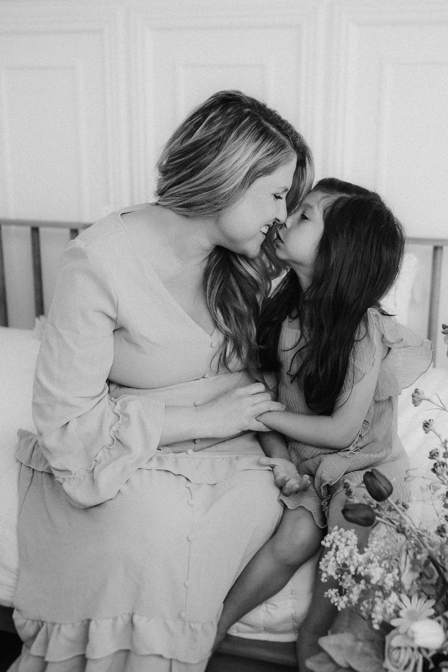 Two people share an intimate kiss while sitting together in romantic black and white photograph.