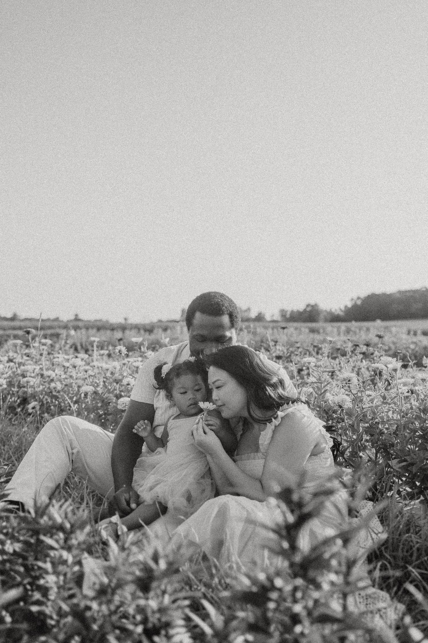 Black and white family portrait in a serene wildflower meadow.