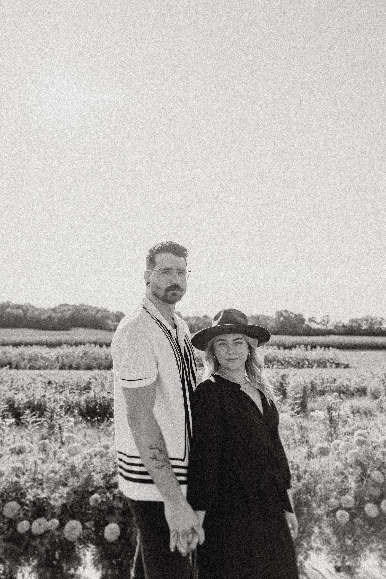 A striking black and white portrait of a couple in a flowering field.