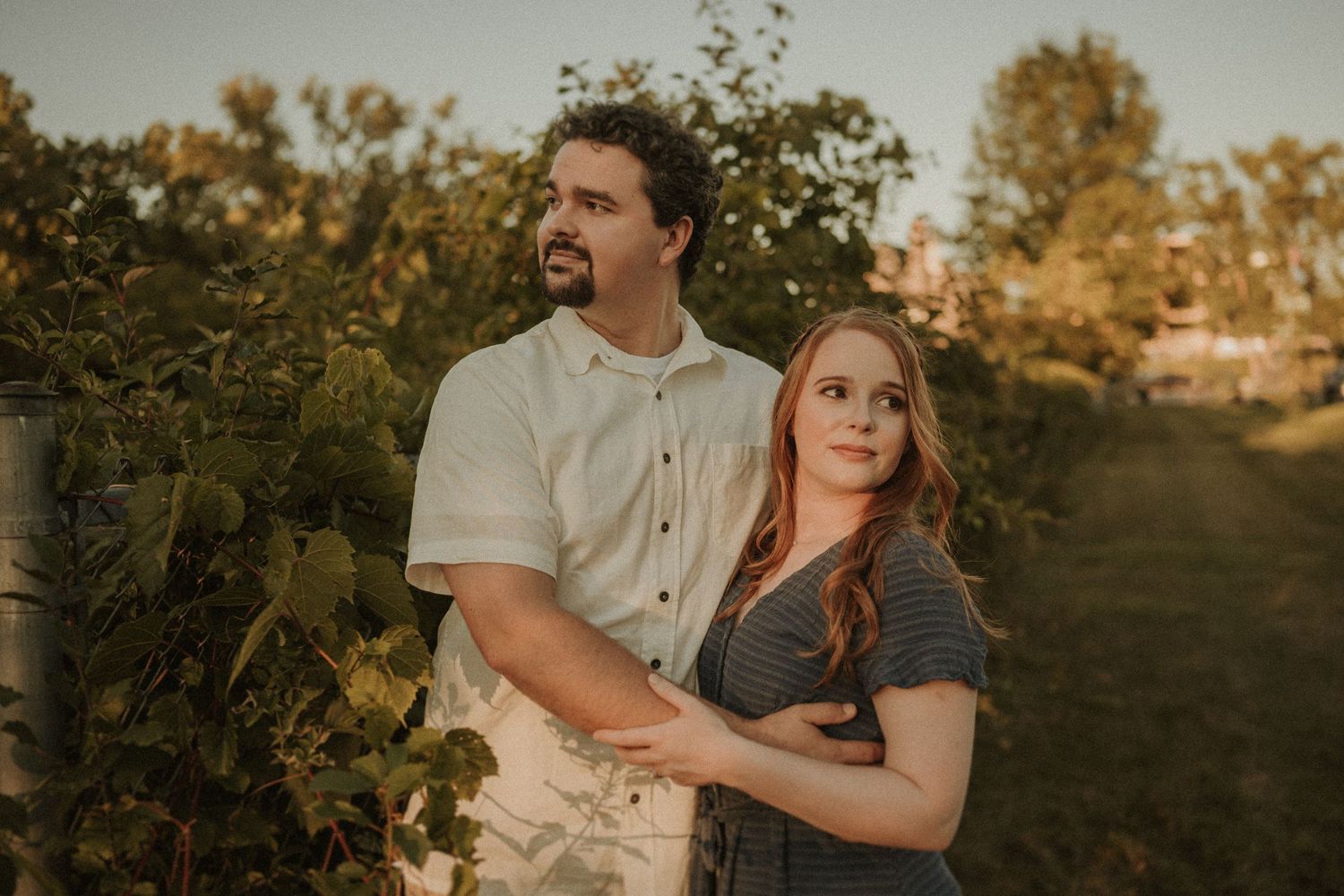 A couple shares an intimate moment together in a garden during sunset.
