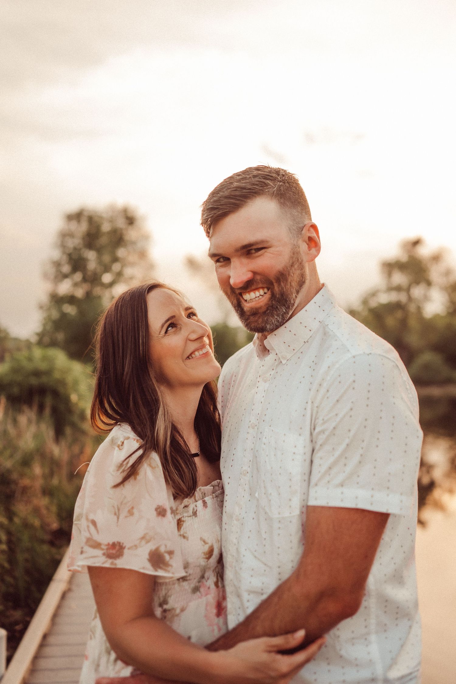 Happy couple sharing an intimate moment on a wooden walkway during golden hour.