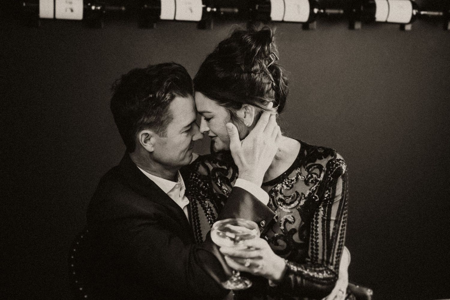 Romantic black and white photograph of couple sharing an intimate moment in dim lighting.