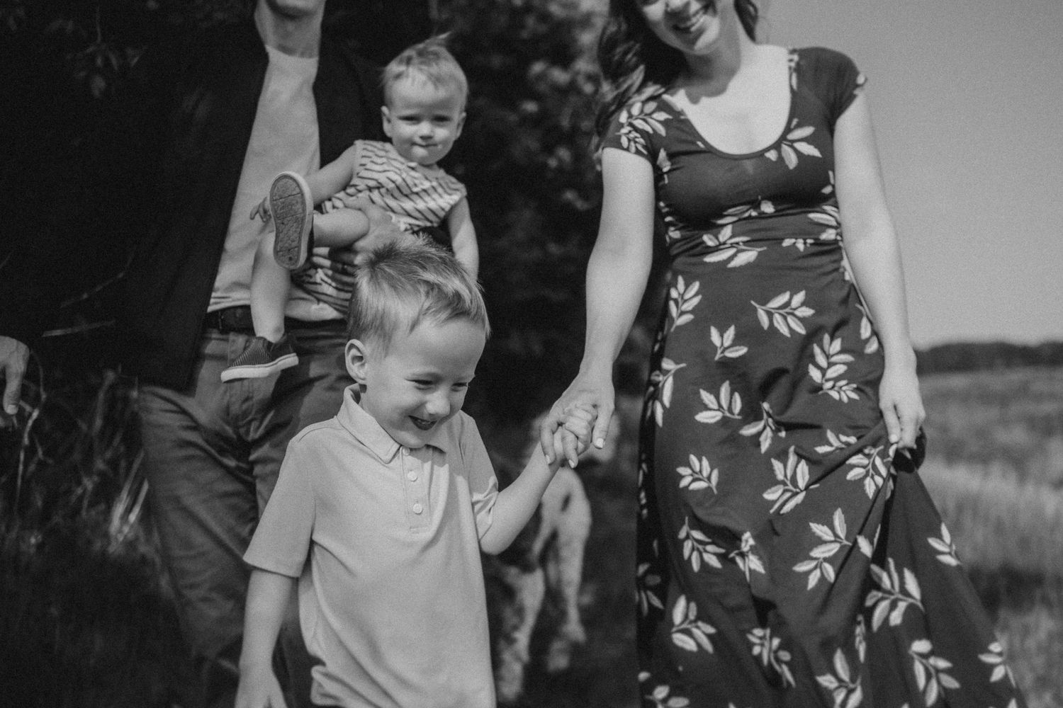 Black and white photo of family walking together outdoors in nature.