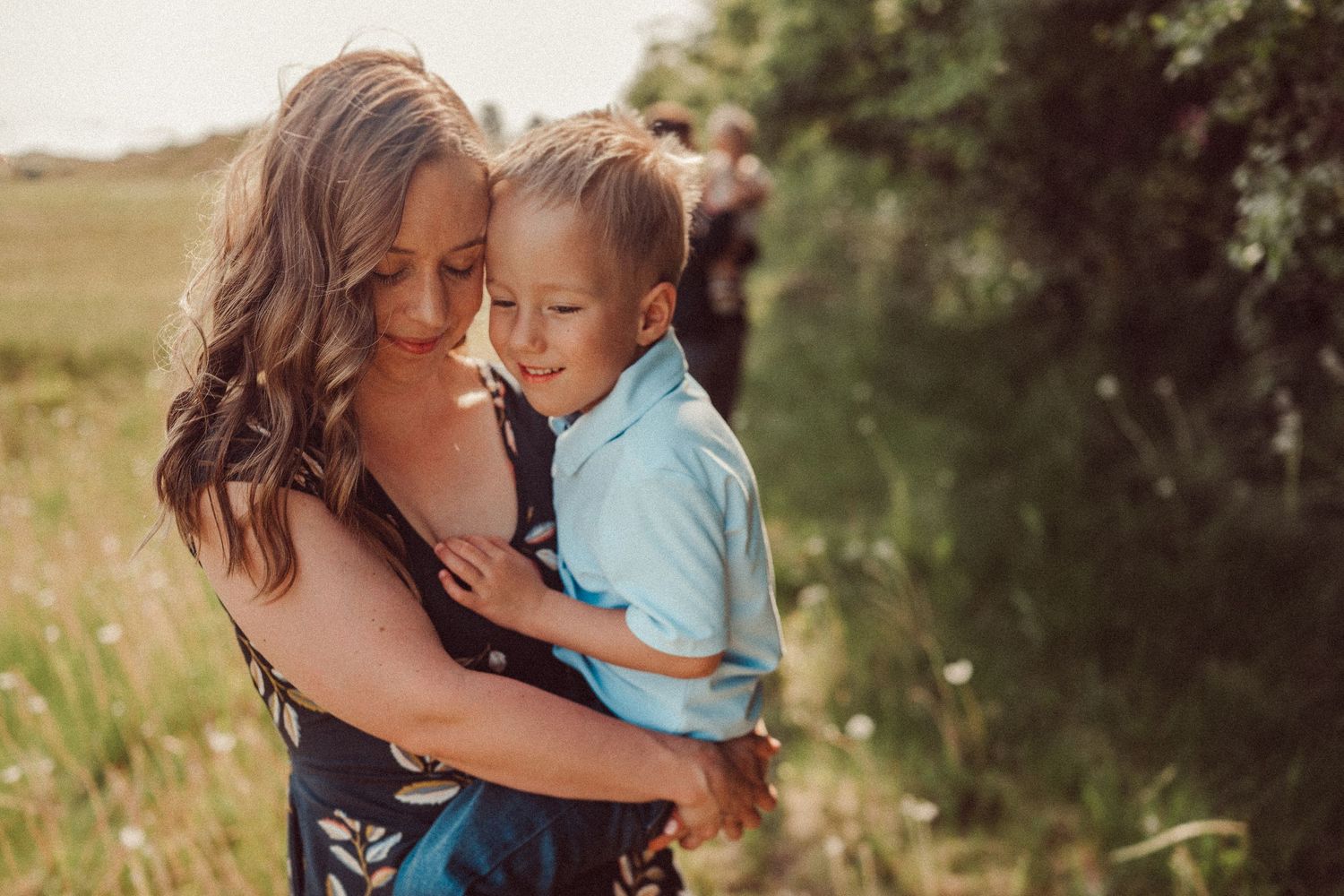 A tender moment captured between parent and child in a sunlit summer field.