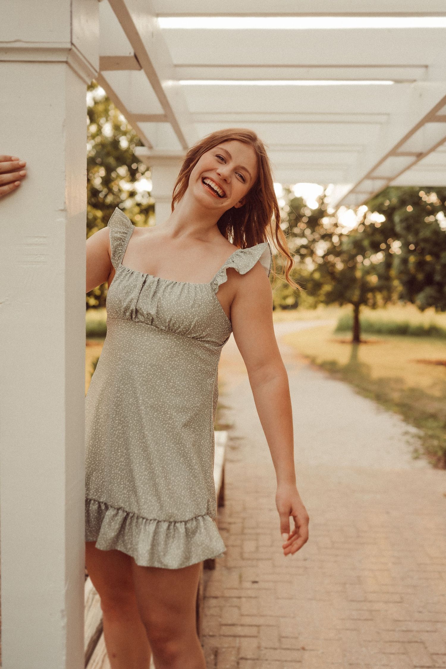 Joyful summer portrait under white pergola with warm lighting.