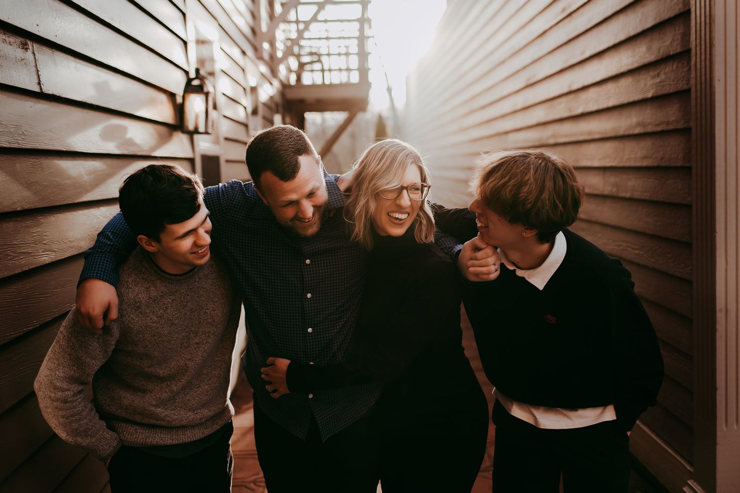Candid laughing moment captured between wooden buildings in natural light.