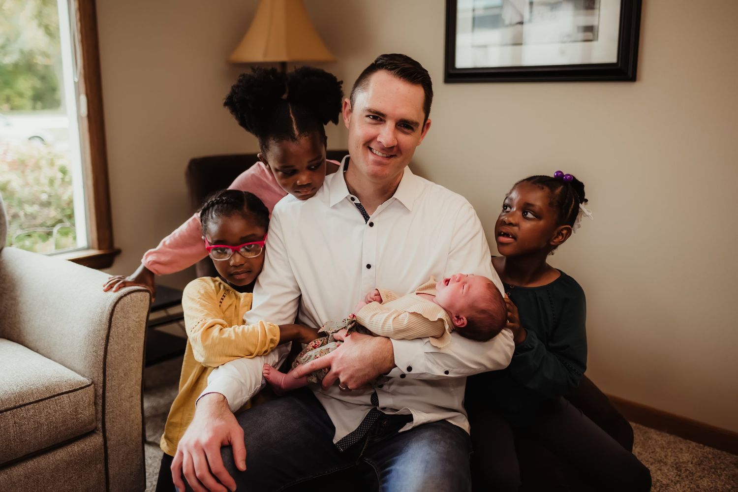Family gathered on couch sharing special moment with newborn baby.