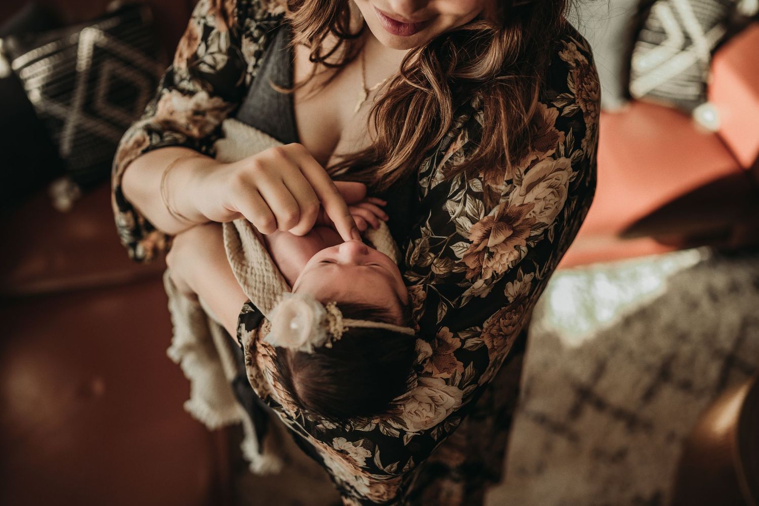 Intimate portrait of caregiver holding sleeping baby in floral patterned dress.