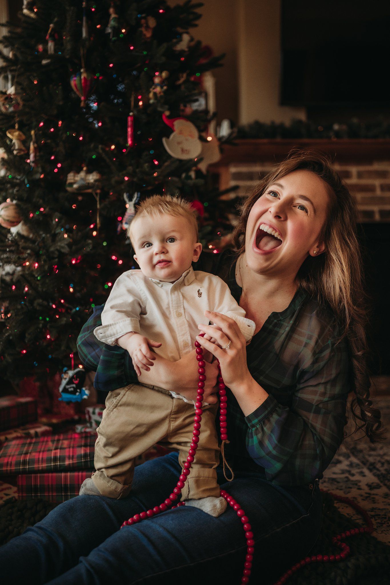 Candid holiday moment featuring laughter and red beaded decorations by a Christmas tree.