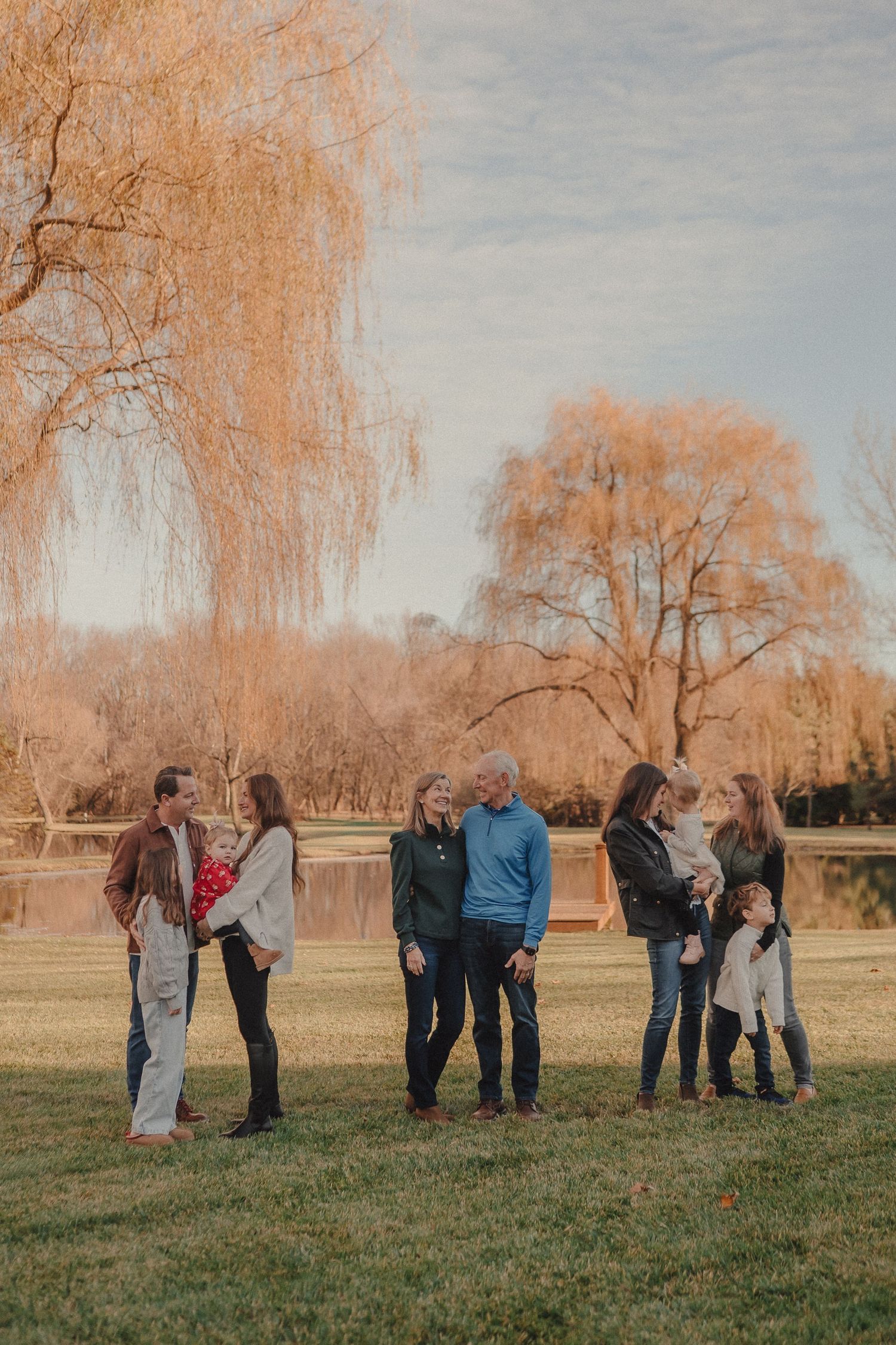 A group of people gathered outdoors in autumn with orange trees in the background during a casual photoshoot.