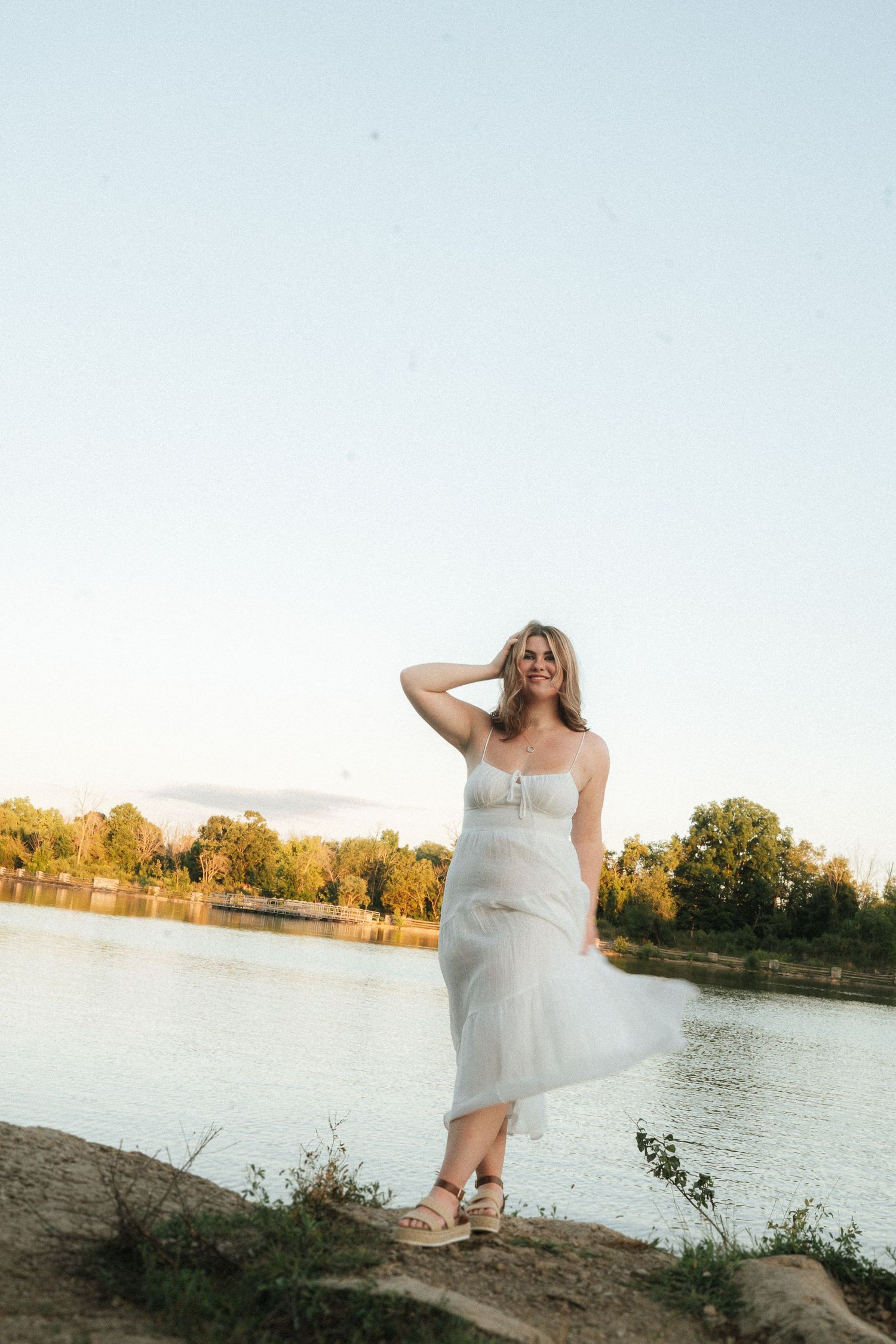 A serene lakeside portrait session at sunset with golden light reflecting on the water.