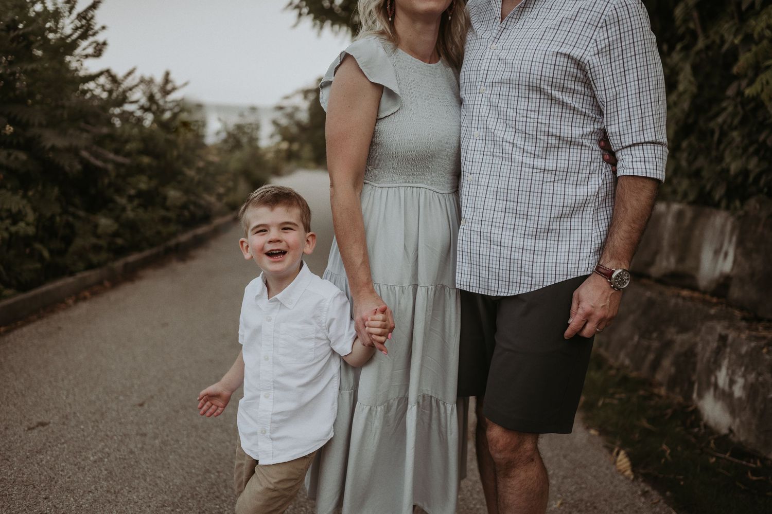 A relaxed family portrait on a tree-lined path with stone retaining wall.