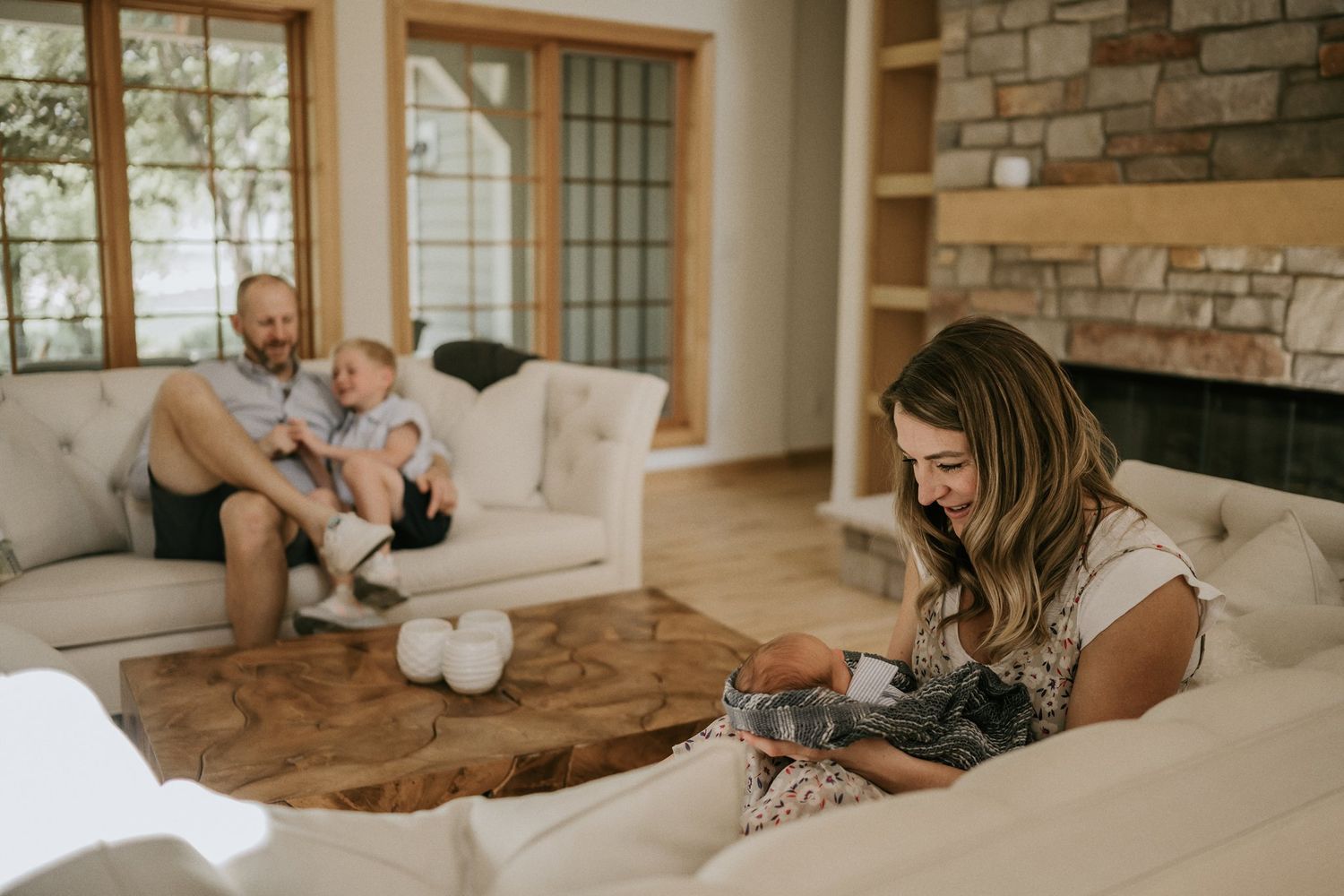 Family relaxing together in modern living room with stone fireplace and natural light.