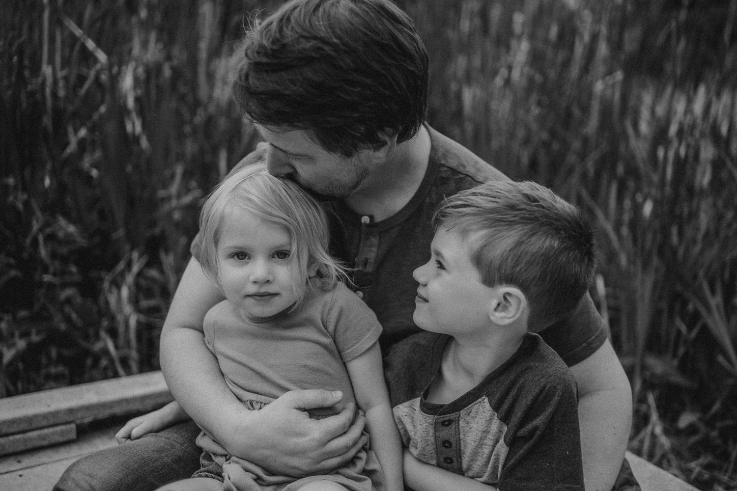 Black and white portrait of family members sharing an intimate moment outdoors.