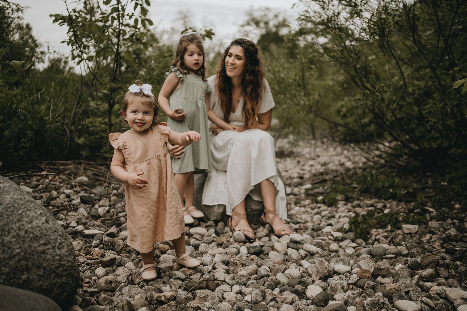 An intimate family portrait taken on a rocky path surrounded by natural foliage.