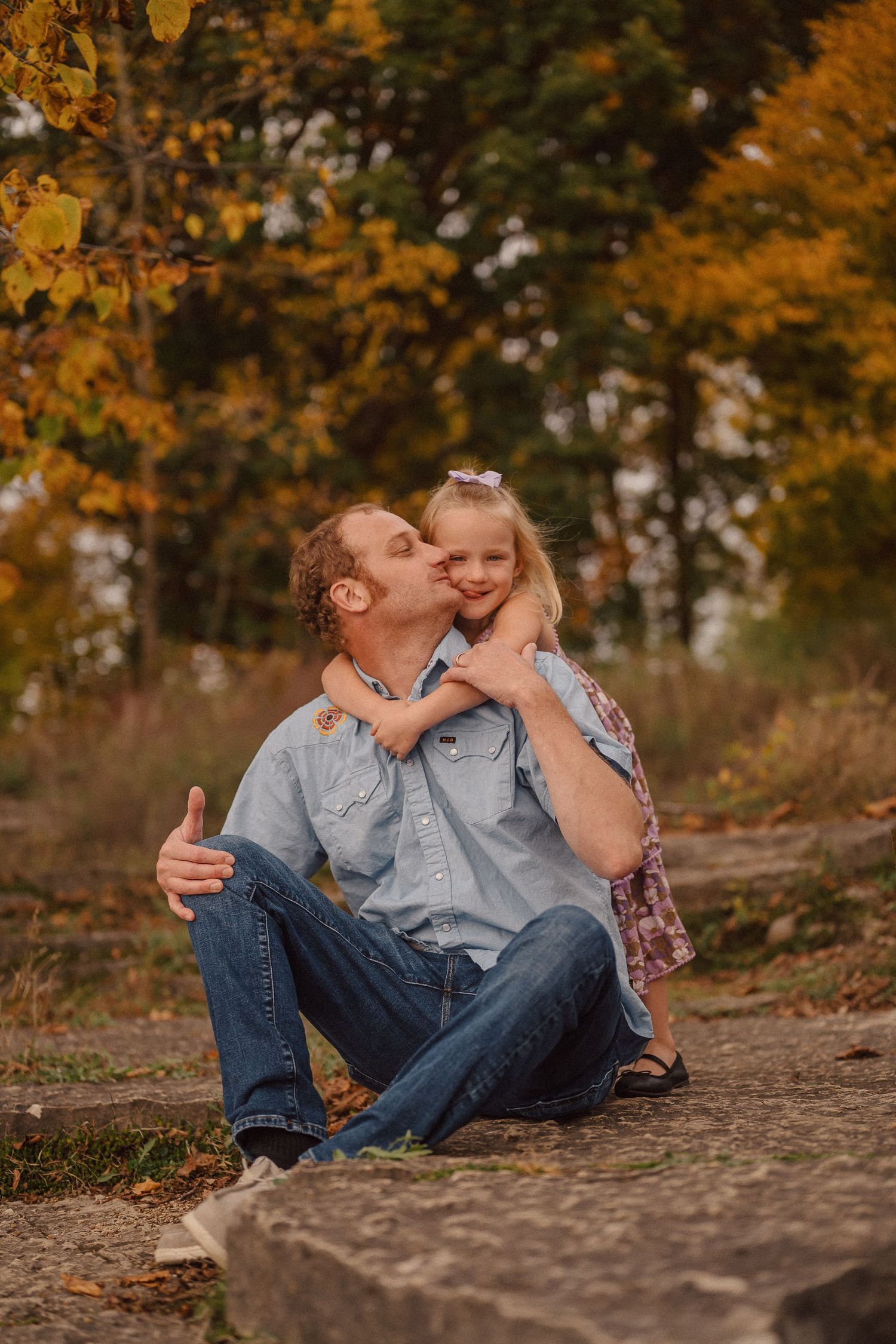 Sweet family moment captured on rocks with beautiful fall colors in the background.