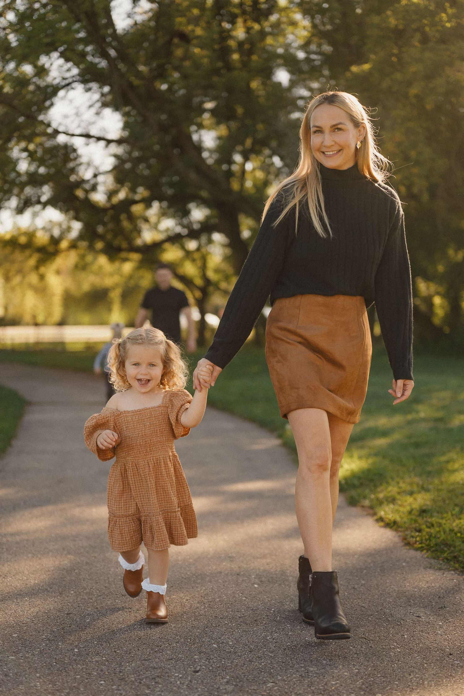 Two people walking together on a path during golden hour in autumn, showing close-up of their legs.